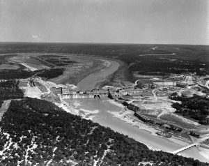 A black-and-white photo from 1938 showing the construction of Mansfield Dam with water flowing downstream, illustrating the early stages of this critical infrastructure. Photo rights granted by LCRA